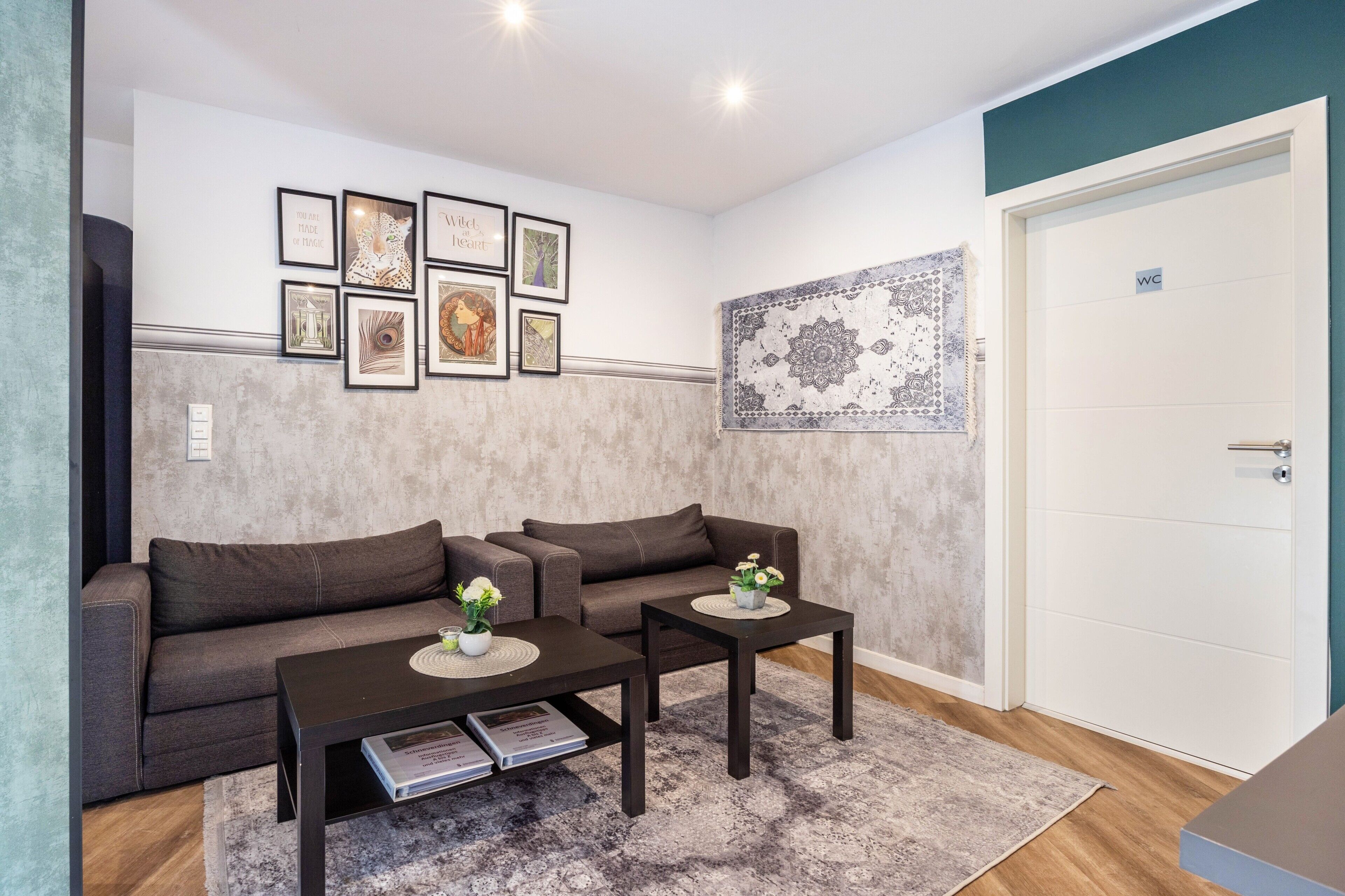 A living room with a sofa, two coffee tables, a rug, and a wall with framed pictures.