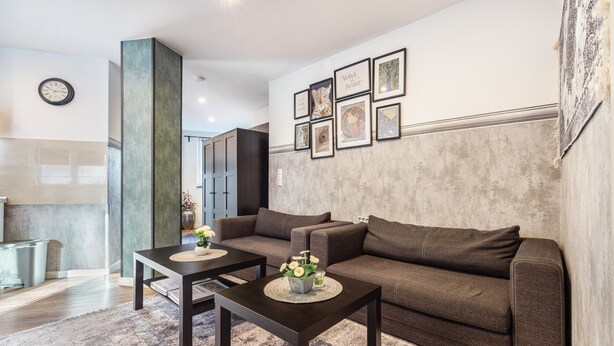 Ein Wohnzimmer mit einer Couch, zwei Couchtischen, einer Uhr und gerahmten Bildern an der Wand.