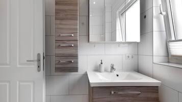 A modern bathroom with a white sink, wooden vanity, and a large mirror.