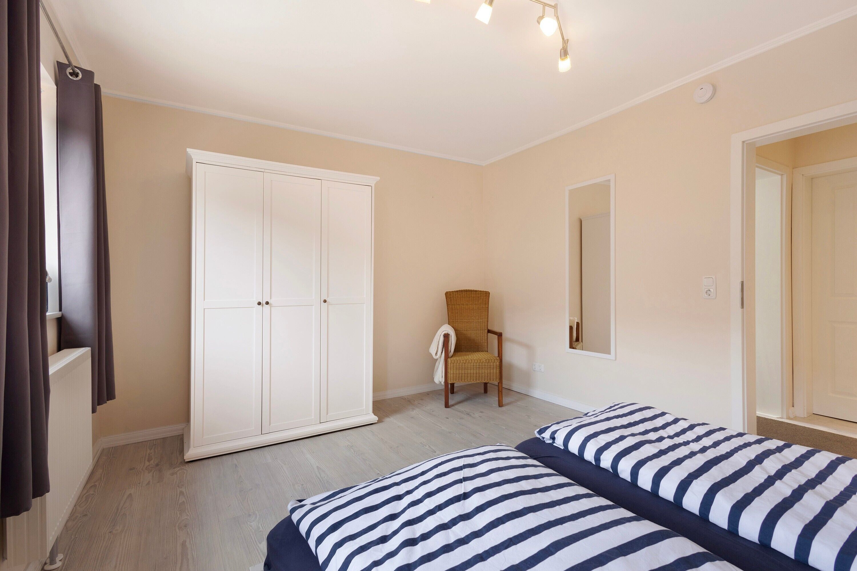 Una camera da letto con un letto, un armadio, una sedia e uno specchio.