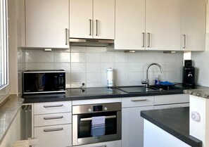 A modern kitchen with stainless steel appliances, a microwave, oven, and a coffee maker.