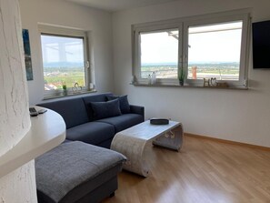 Un salon moderne avec un canapé, une petite table et une fenêtre donnant sur un beau paysage.