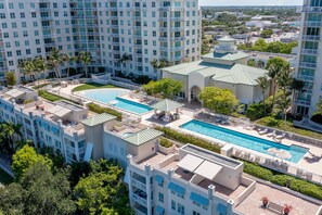 A high-rise hotel with multiple swimming pools, lush landscaping, and a prominent building with a green roof.