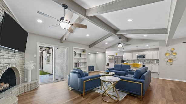 A spacious living room with a fireplace, blue sofas, a coffee table, and a ceiling fan.