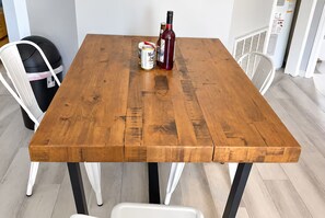 A wooden dining table with chairs, a bottle, and a can of drink.