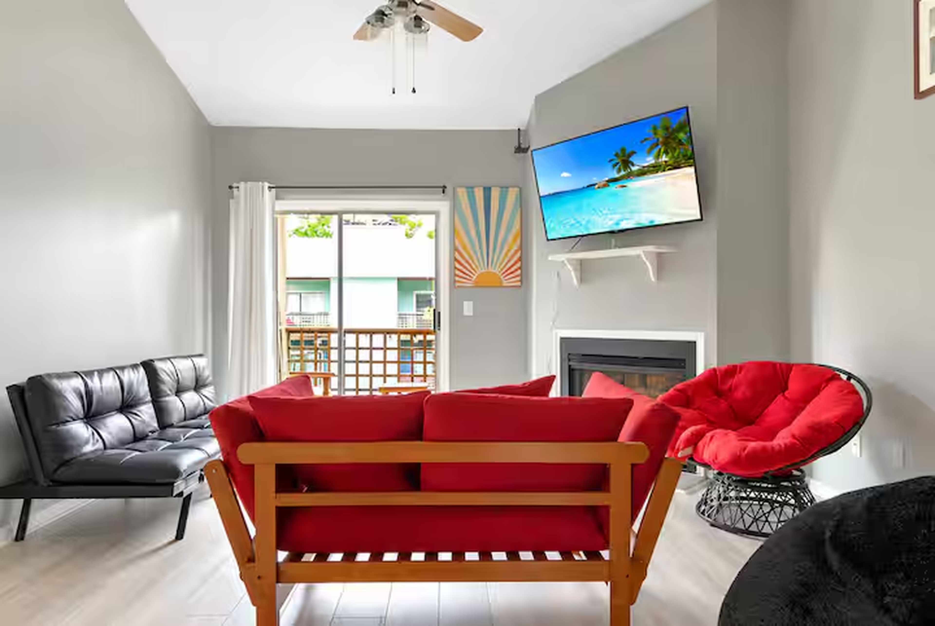 A living room with a sofa, a red chair, a television, and a fireplace.