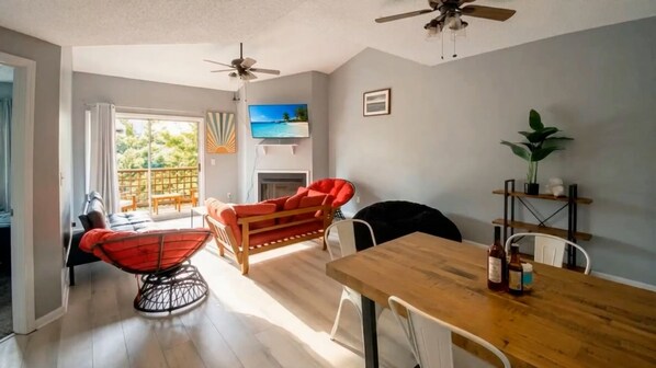 Un salon avec une table à manger en bois, un canapé rouge et des ventilateurs de plafond.