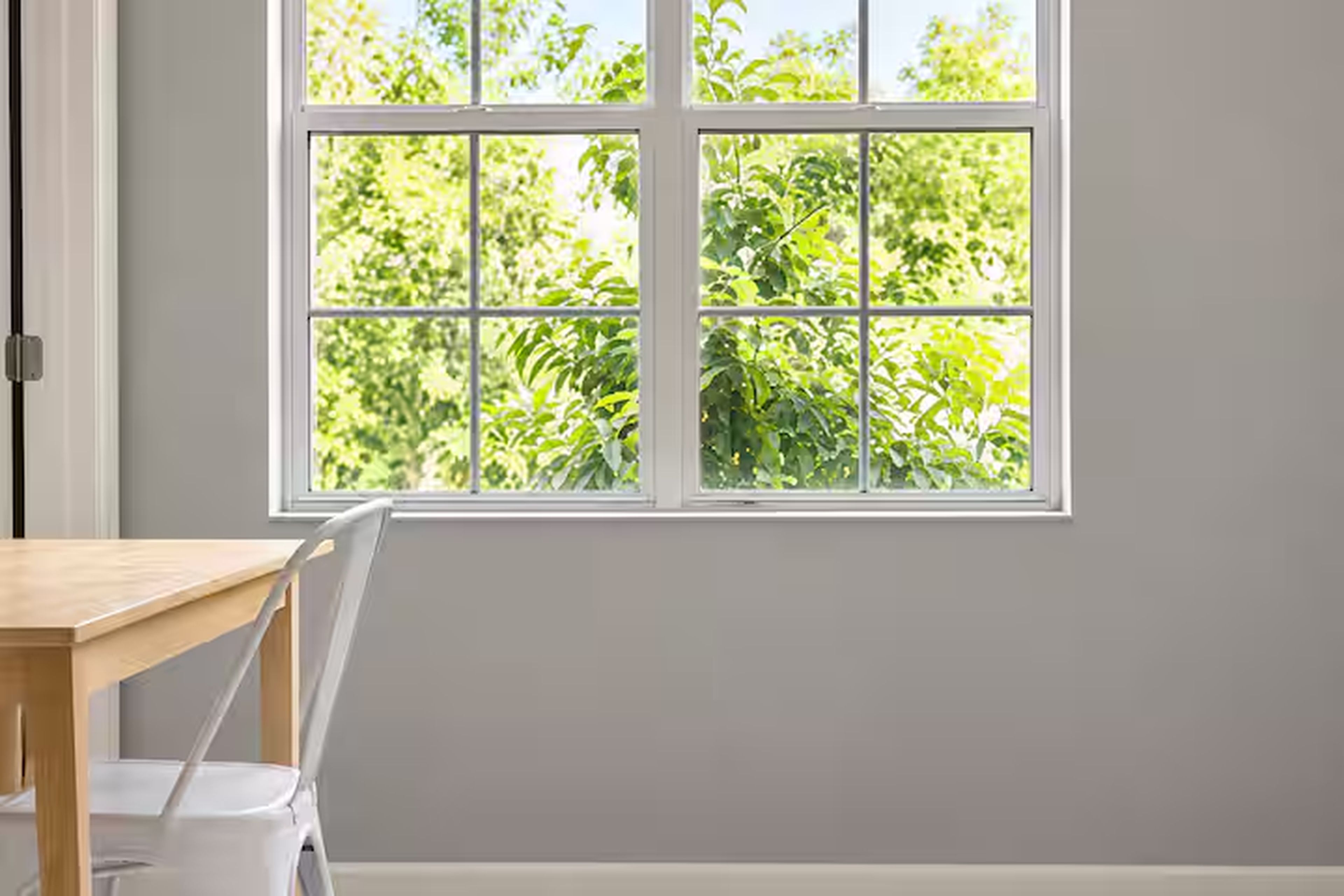 A room with a window, a table, and a chair.