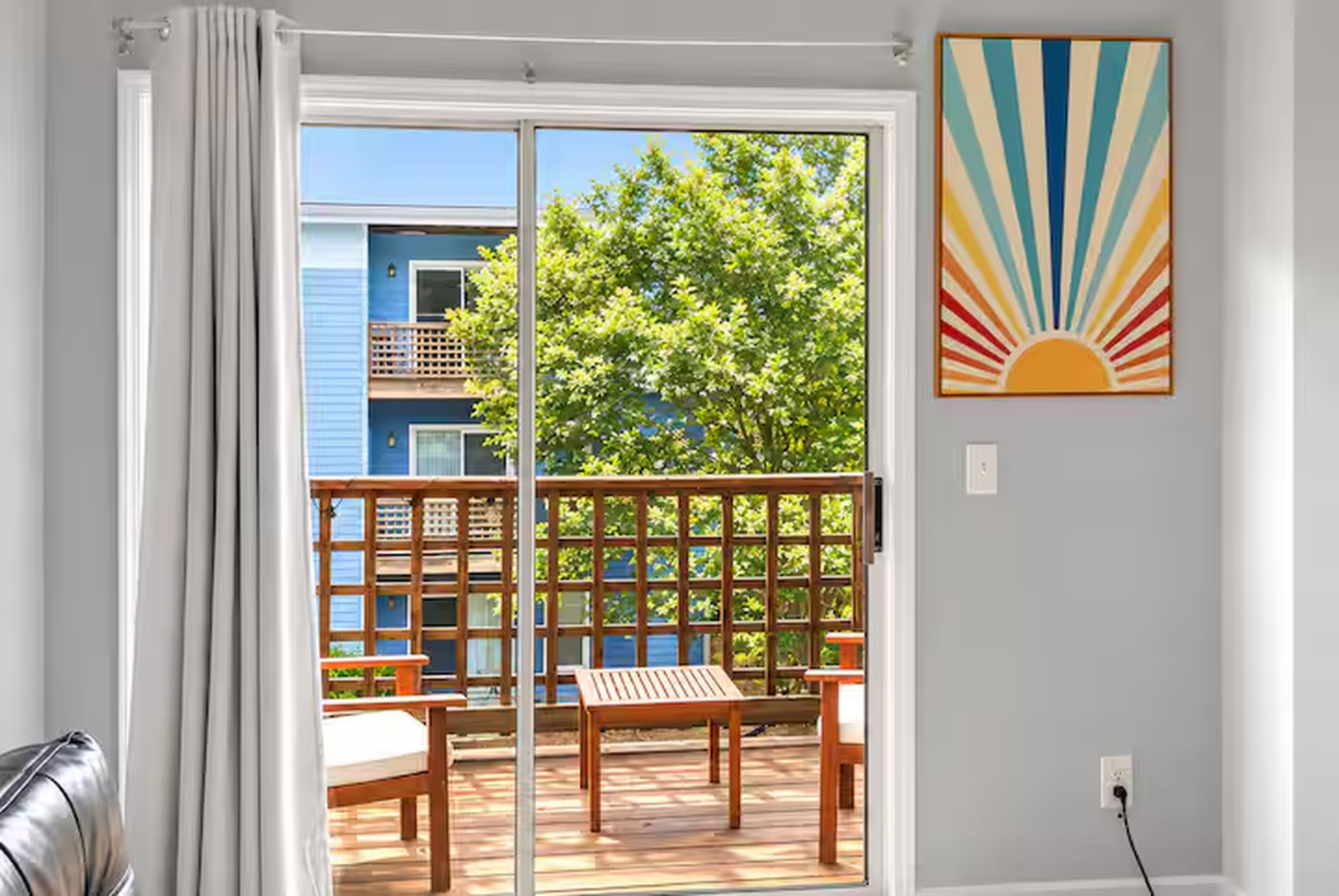 A room with a sliding glass door leading to an outdoor deck with a wooden table and benches.