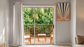 A room with a sliding glass door leading to an outdoor deck with wooden furniture.