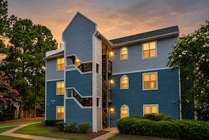 A multi-story residential building with a central staircase, multiple windows, and a well-maintained lawn. - Corporate Retreat: Stylish 2BR, Pool, Balcony (Wilmington)