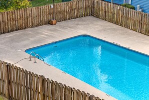 A rectangular swimming pool with a wooden fence surrounding it.