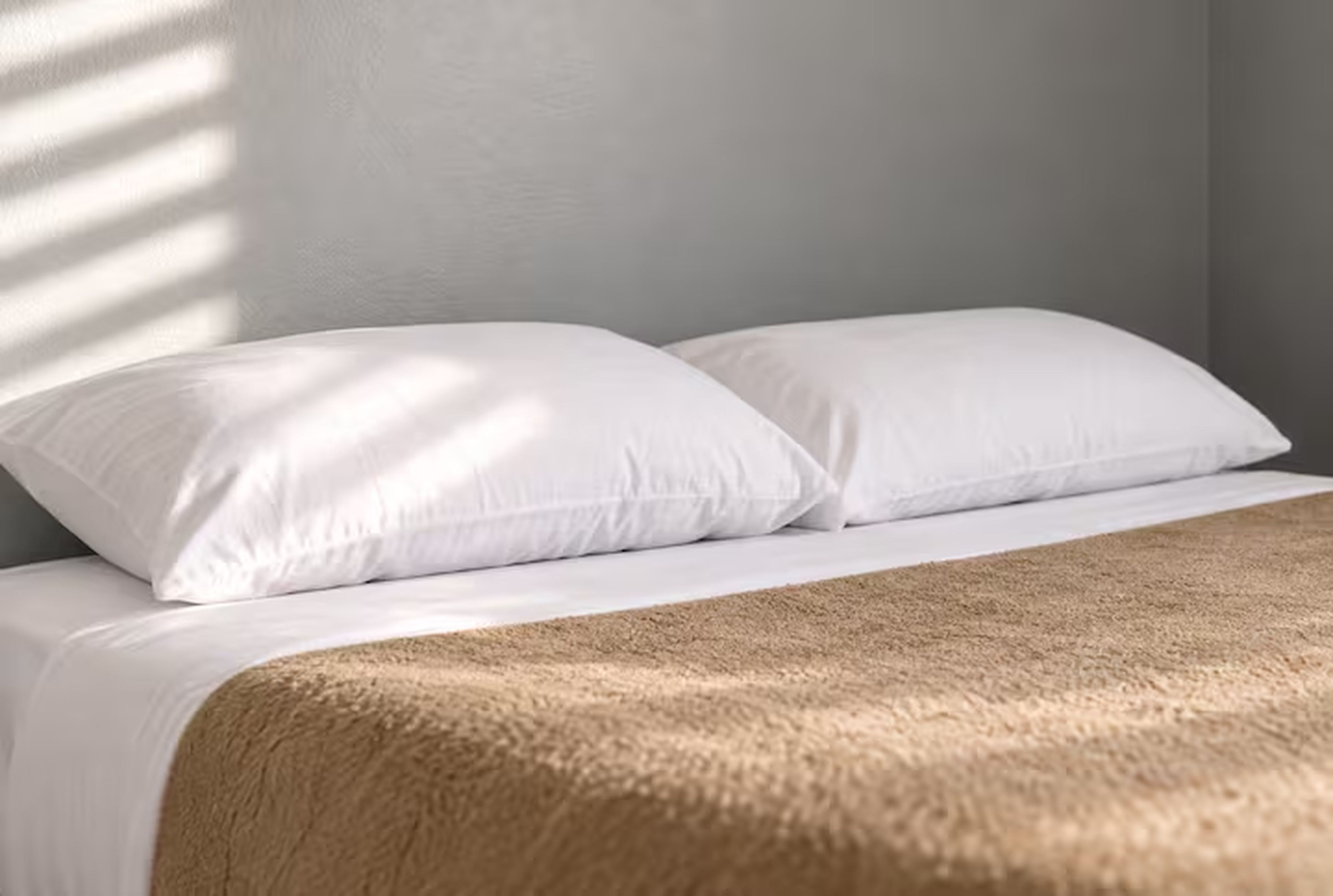 A bed with white bedding and a brown blanket.
