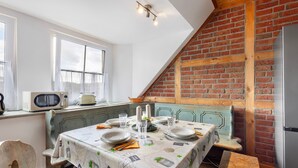 A dining area with a table set for four, a microwave, a refrigerator, and a brick wall. - Apartment 'Wohnung Auf Dem Dorf' with Wi-Fi (Zarpen)