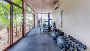 A gym with large windows, exercise balls, dumbbells, and weightlifting equipment. - TAO Penthouse, Private Rooftop SpaTub, Pool Onsite (Tulum)