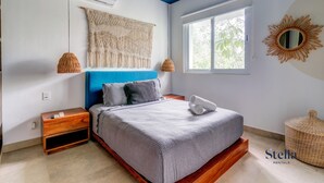 A bedroom with a bed, nightstand, wall-mounted air conditioner, and a large window with a view of trees. - TAO Penthouse, Private Rooftop SpaTub, Pool Onsite (Tulum)