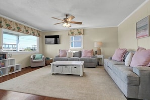 Relax in this inviting living room with a flat-screen TV, comfortable sofas, and a bookshelf.