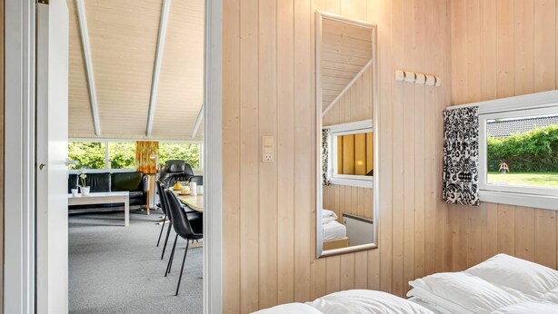 A bedroom with a bed, a mirror, and a window with a view of the outdoors. - "Guja" - 250m from the sea by Interhome (Faxe Ladeplads)