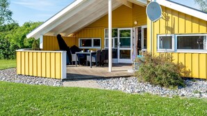 A yellow building with a covered patio, outdoor seating, and a satellite dish. - "Guja" - 250m from the sea by Interhome (Faxe Ladeplads)