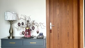 Une porte en bois, une table bleue avec une lampe et une plante décorative.