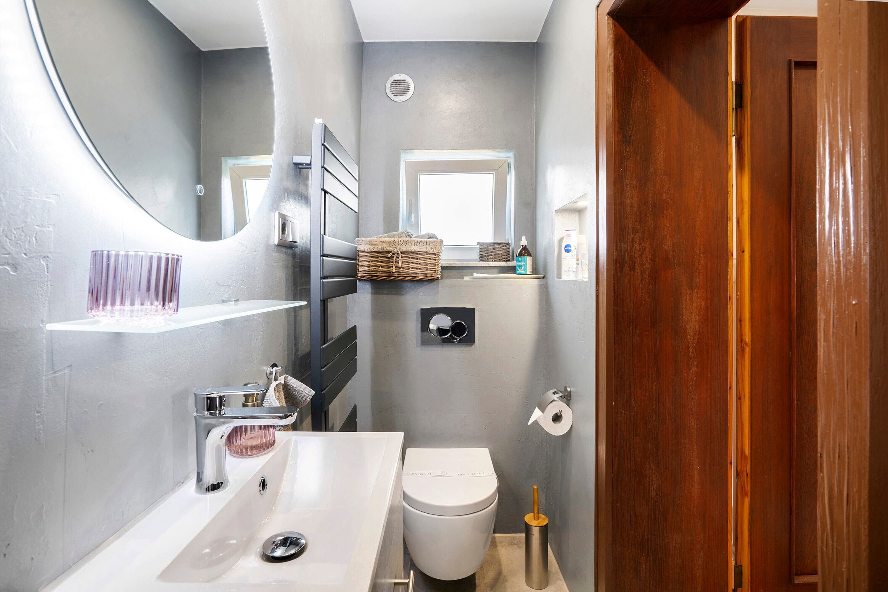 Ein Badezimmer mit Waschbecken, Toilette, Spiegel und Holztür.