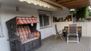 A covered patio area with a wicker sofa, a small table, and chairs. - Apartment 'Collenberger Ferienwohnung Schäfer' with Private Terrace, Garden & Wi-Fi (Collenberg)