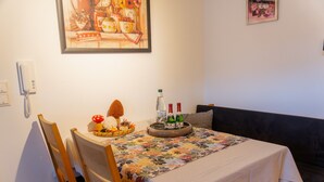 A dining area with a table set for two, a floral tablecloth, and a bottle of water. - Apartment 'Collenberger Ferienwohnung Schäfer' with Private Terrace, Garden & Wi-Fi (Collenberg)
