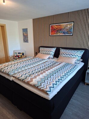 Ein modernes Schlafzimmer mit einem großen Bett, Streifenmuster-Tapete und einem Bild an der Wand.