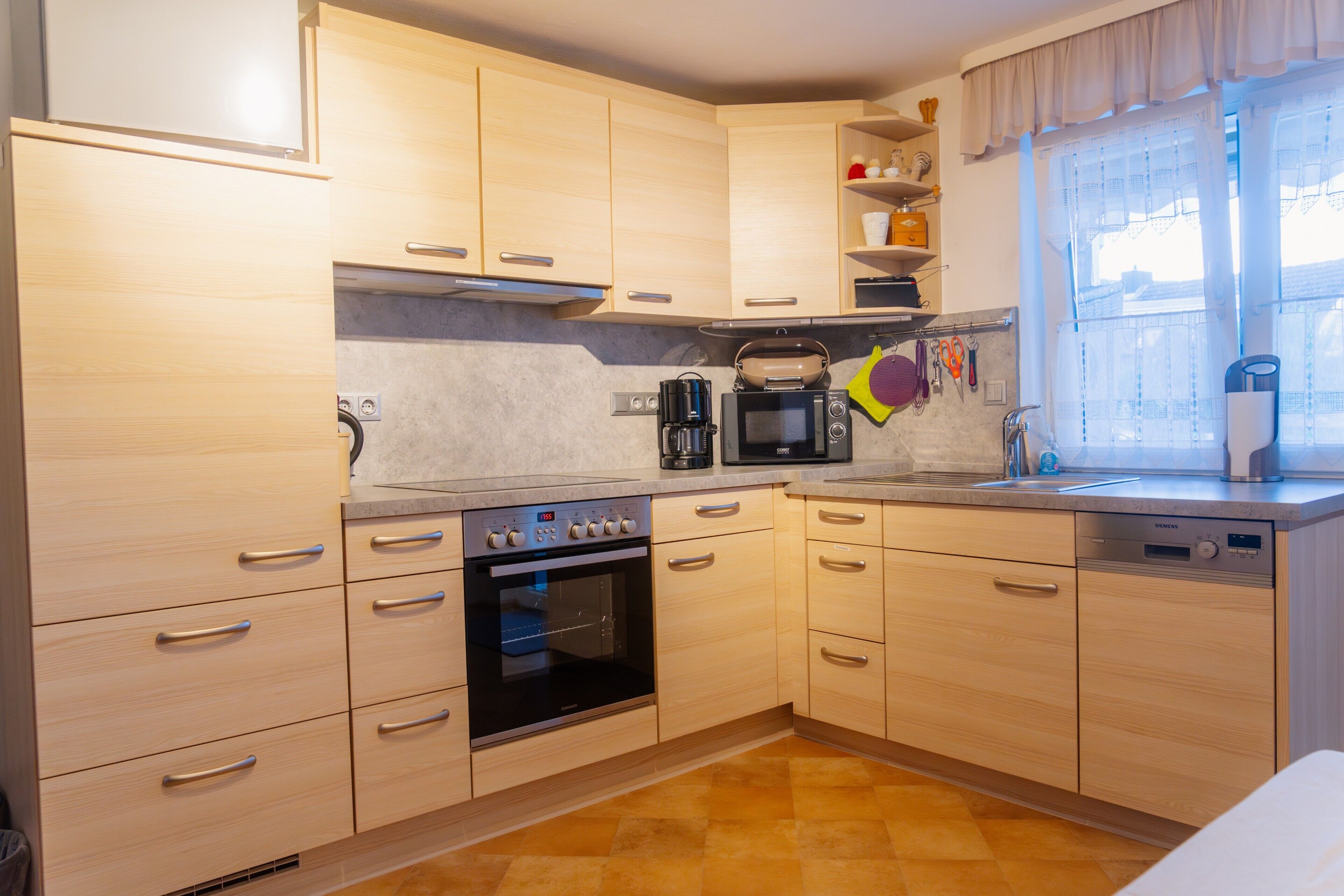 Eine Küche mit Holzausstattung, einer Mikrowelle, einem Backofen und einem Spülbecken.