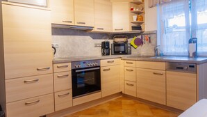 A kitchen with wooden cabinets, a microwave, an oven, and a sink. - Apartment 'Collenberger Ferienwohnung Schäfer' with Private Terrace, Garden & Wi-Fi (Collenberg)