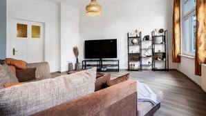 Ein modernes Wohnzimmer mit einer Couch, einem Fernseher und Regalen.