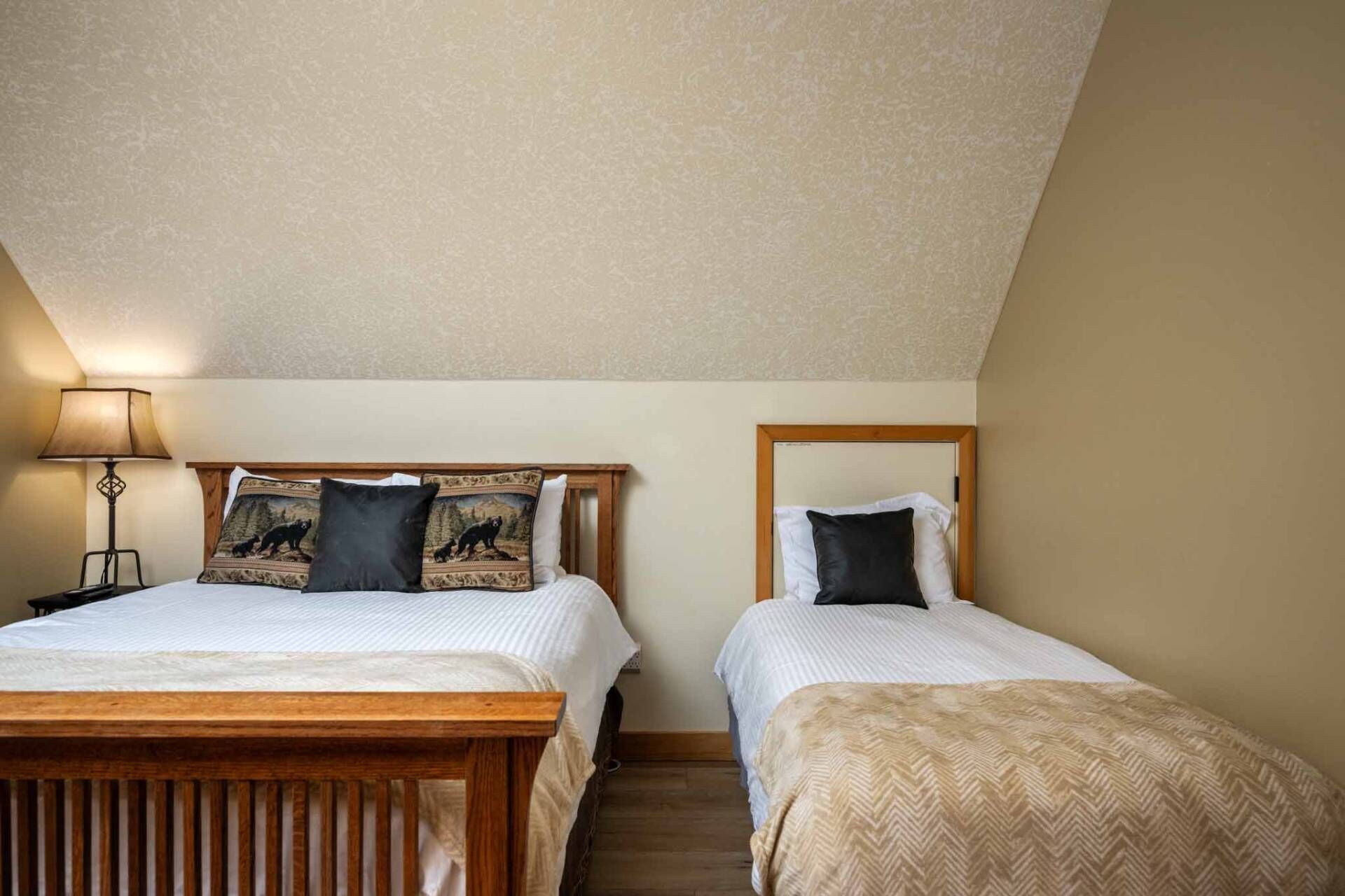 A room with two beds, a lamp, and a patterned wall.