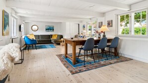 A spacious living area with a dining table, blue chairs, a sofa, and a fluffy white chair. - "Øde" - 100m from the sea by Interhome (Svaneke)