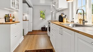 A modern kitchen with white cabinetry, wooden countertops, a built-in oven, and a window providing natural light. - "Øde" - 100m from the sea by Interhome (Svaneke)