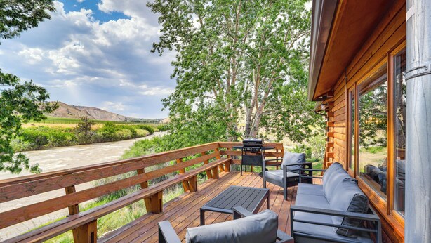 A wooden deck with outdoor seating, overlooking a river and hills. - Dubois Riverfront Lodge w/ On-Site Fishing & Views (Dubois)