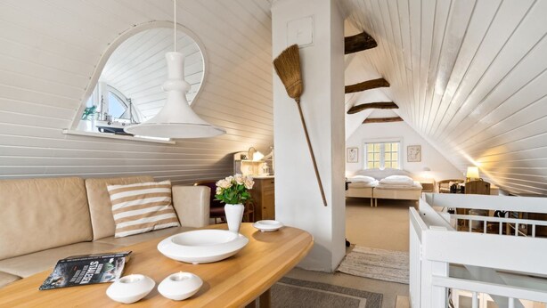 Un acogedor apartamento tipo loft con una mesa de madera, un sofá y un ventanal grande.