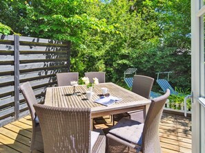 Une terrasse extérieure avec une table en bois et des chaises en osier.