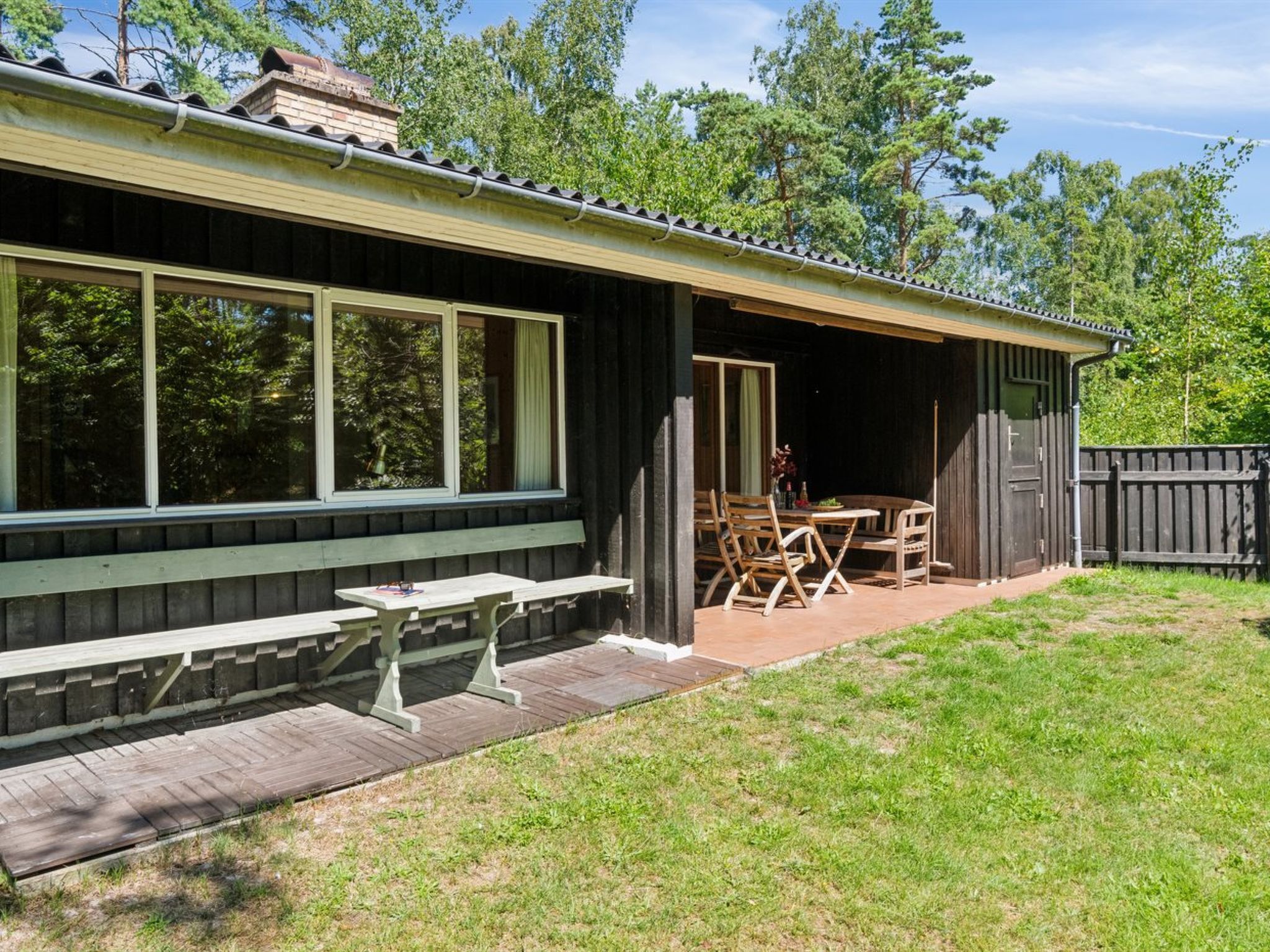 Une cabane en bois dotée d’un patio couvert, d’une table de pique-nique et de chaises.