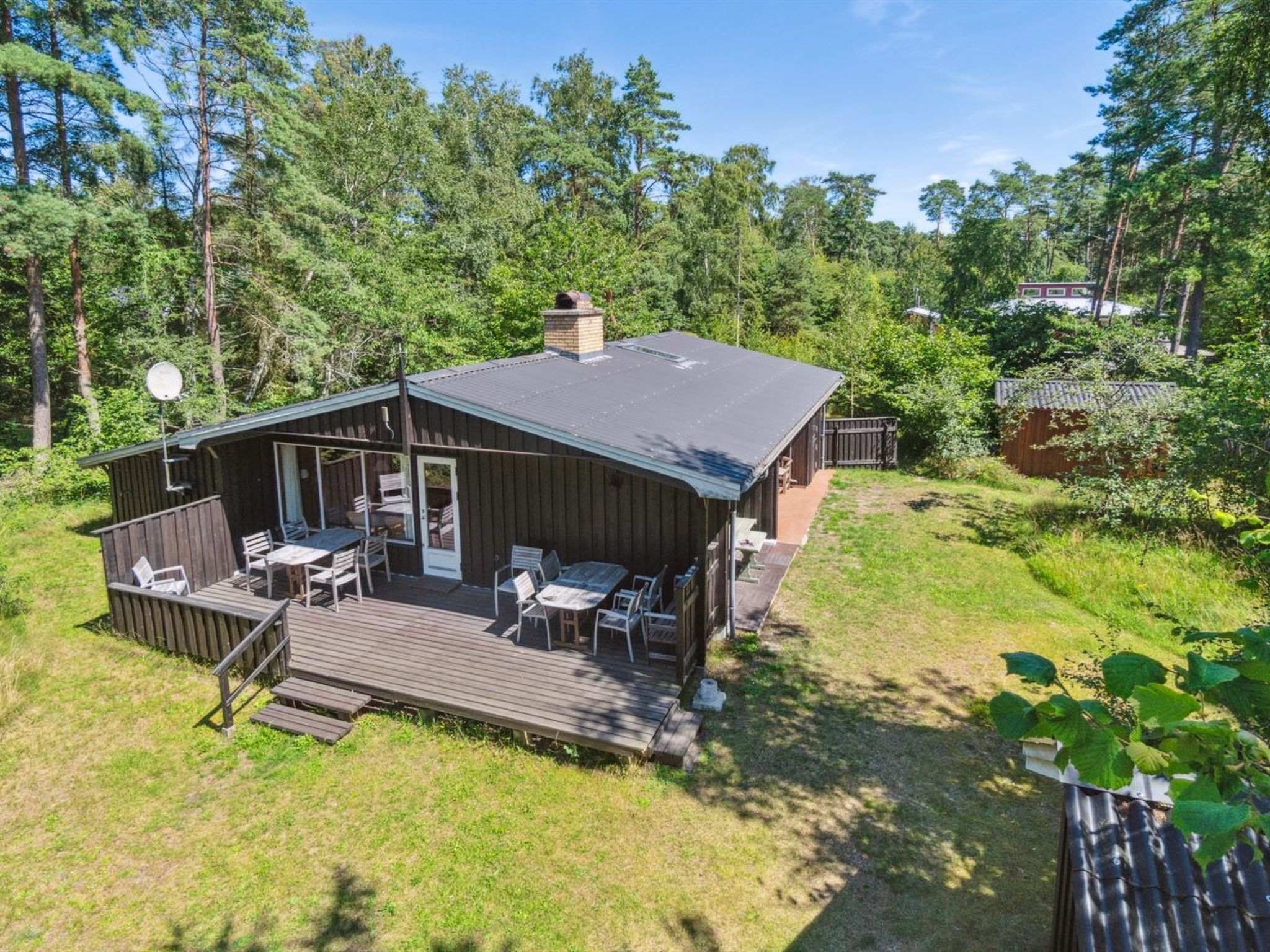 A cabin with a deck, outdoor seating, and a chimney.