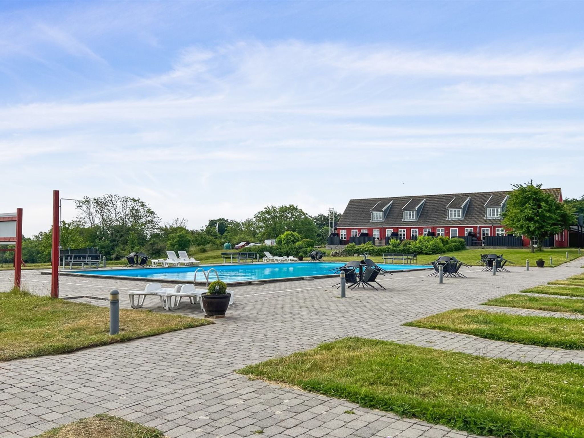 Ein Poolbereich mit Liegestühlen und einem roten Gebäude im Hintergrund.