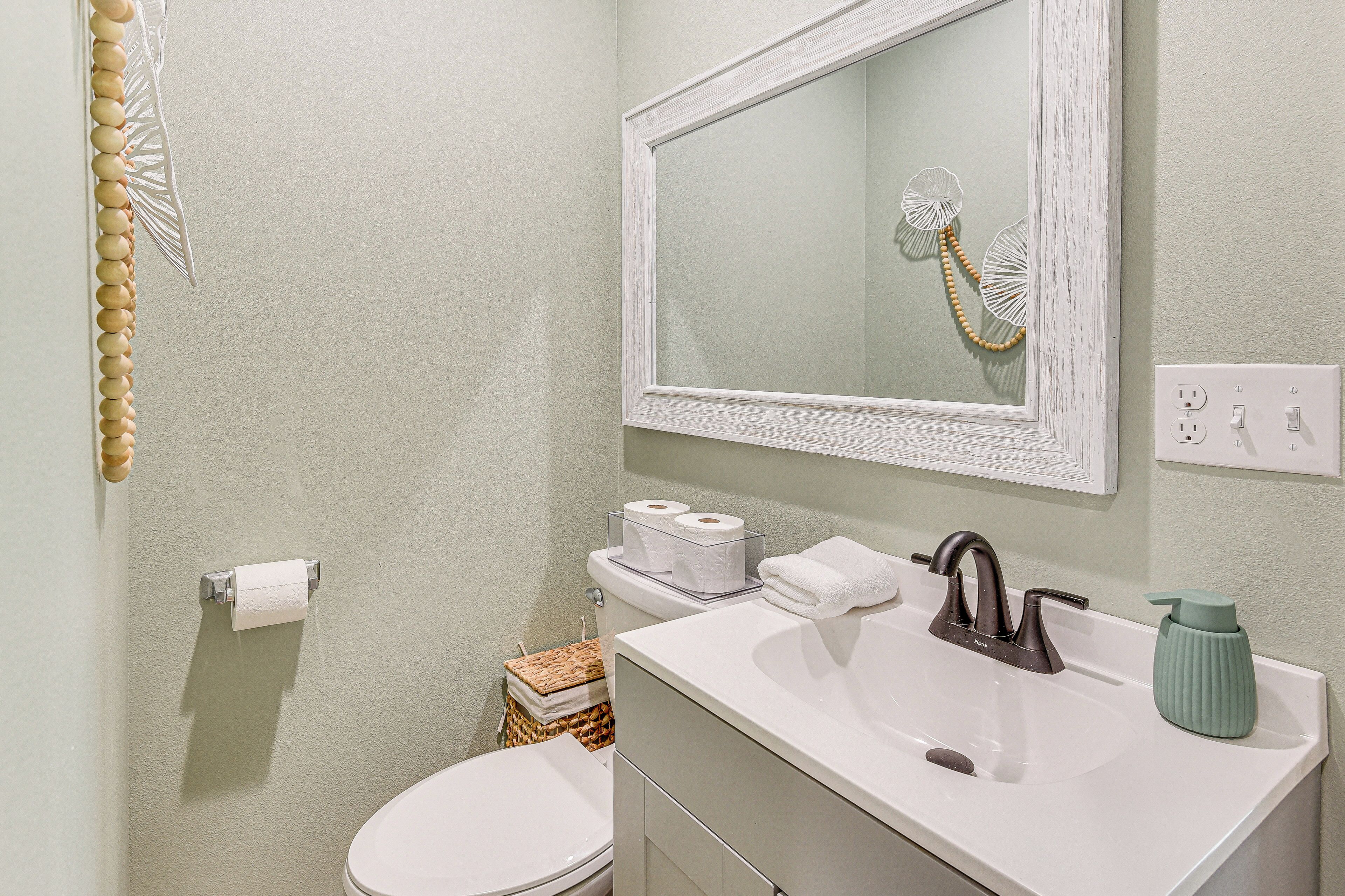 Un baño con lavamanos blanco, un espejo y un inodoro.