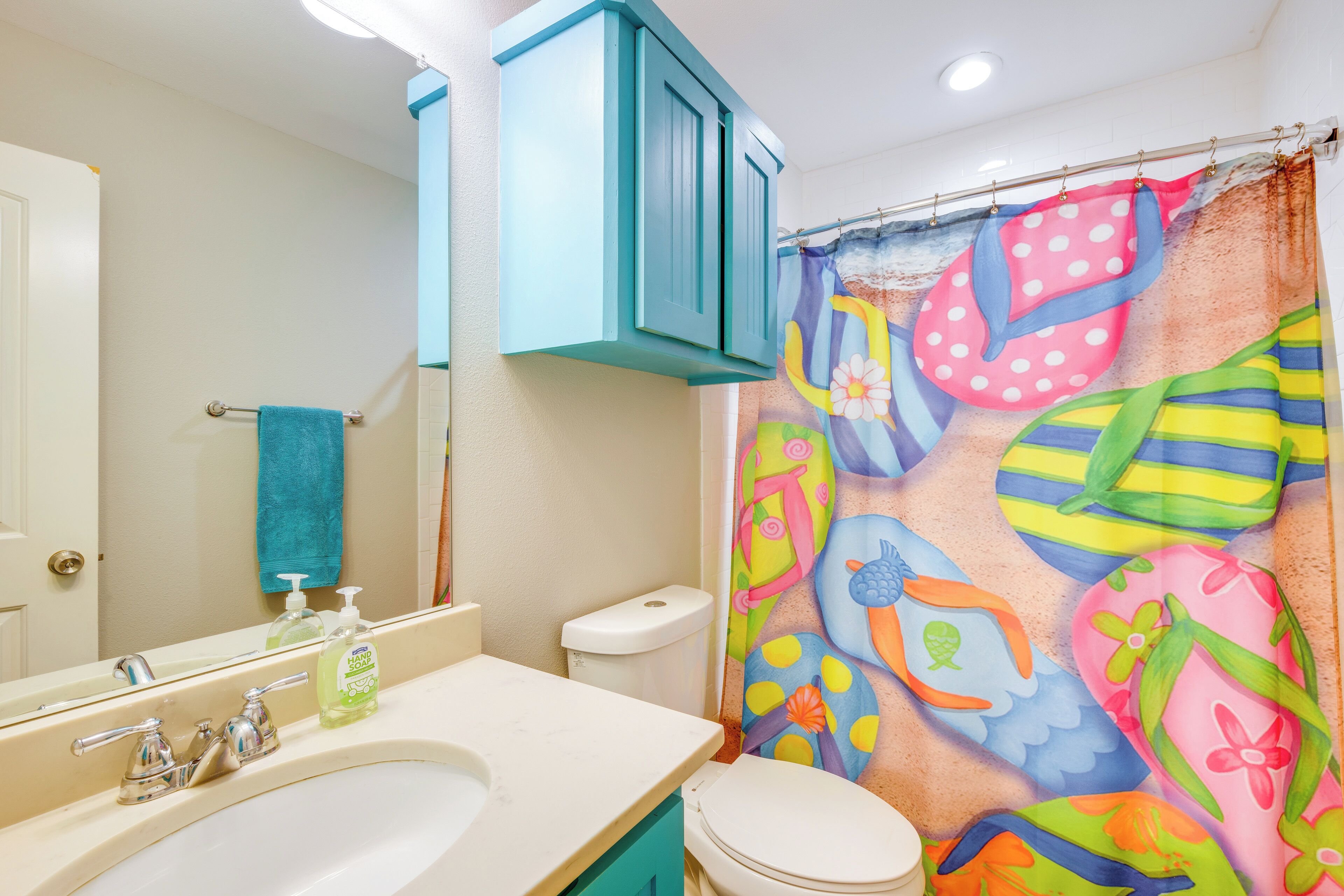 A bathroom with a sink, toilet, and a colorful shower curtain.