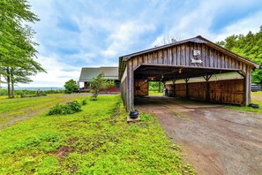 Une grange rustique dotée d’une entrée couverte, entourée d’une végétation luxuriante et sous un ciel dégagé.