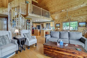Une pièce spacieuse de style loft, dotée d’un escalier en bois, d’un canapé, d’une table basse et d’un coin cuisine.