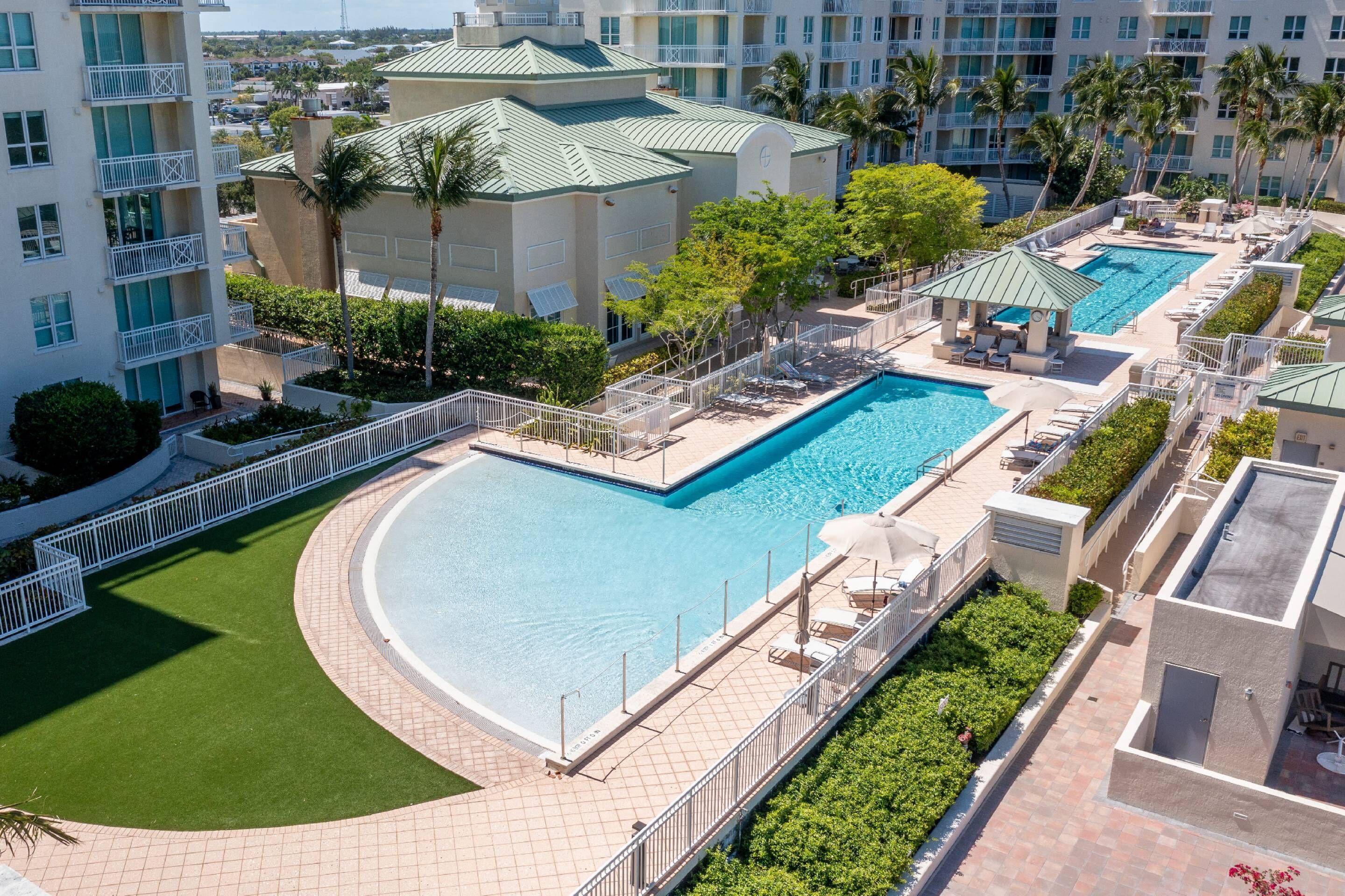 A hotel with a large swimming pool, multiple balconies, and lush landscaping.