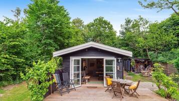 Une petite cabane dotée d’une terrasse, entourée d’une végétation luxuriante.