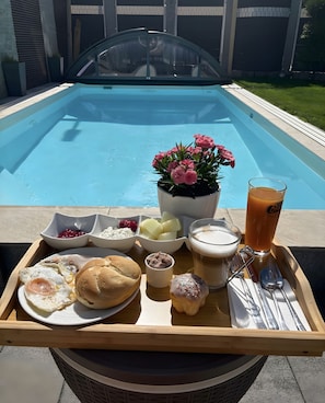 Un plateau de petit-déjeuner avec de la nourriture et des boissons, servi au bord de la piscine.