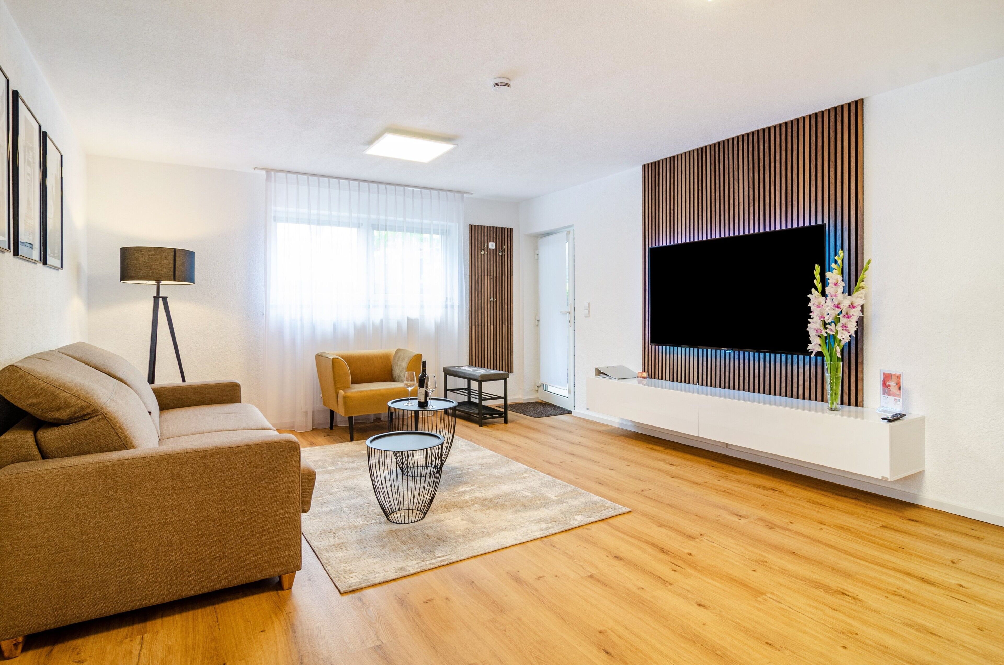 Ein modernes Wohnzimmer mit einer Couch, einem Couchtisch, einem Fernseher und einer dekorativen Vase.