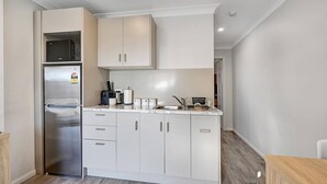 Une cuisine moderne avec des meubles blancs, un réfrigérateur en acier inoxydable et un four à micro-ondes.