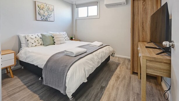 Une chambre à coucher avec un lit, une table de chevet et un meuble pour la télévision.